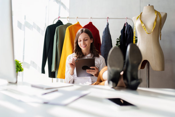 美丽的女人时装设计师时尚的工作与彩色的布。在工作室工作的时装设计师图片下载