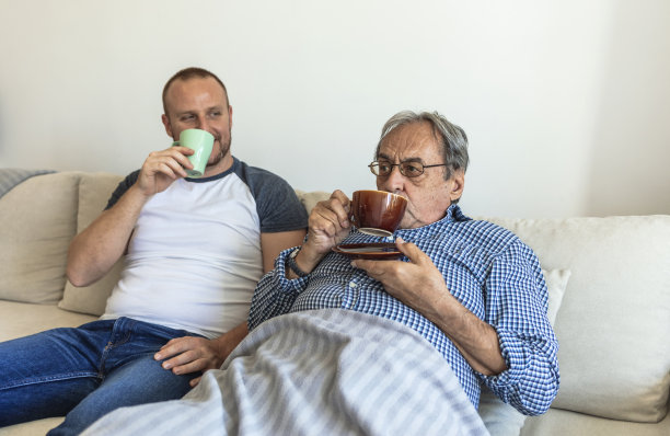无忧无虑轻松真诚快乐的两代男性家庭，年幼的儿子和年迈的高级父亲参与愉快的交谈，聊着分享生活新闻，在家里喝着热茶或咖啡。图片下载