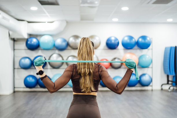 美丽的女人在健身房用橡皮筋进行练习。图片下载