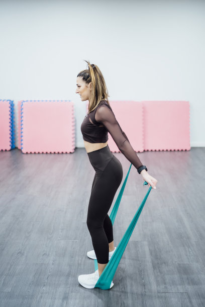 美丽的女人在健身房用橡皮筋进行练习。图片下载