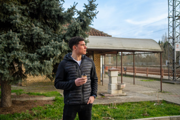 年轻男子站在外面带外卖咖啡-资料照片。图片下载