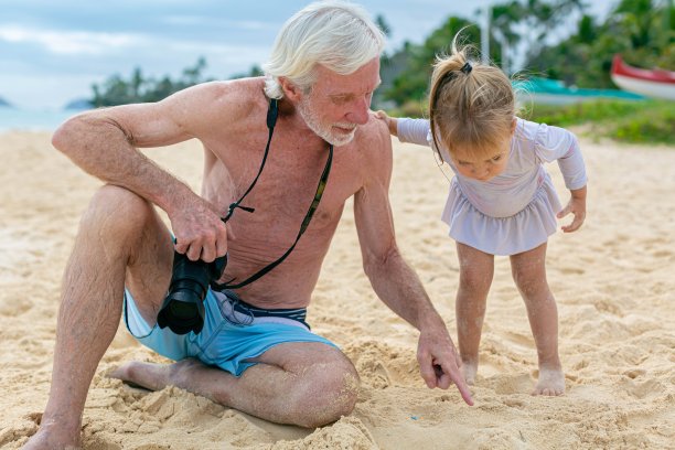 一位爷爷和他的孙子在户外海滩上玩耍。孩子们在大自然中学习。图片下载