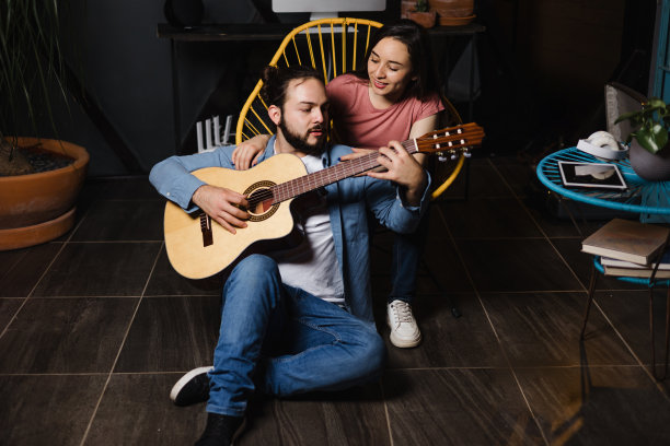 拉丁美洲的墨西哥，一对西班牙情侣在弹吉他，女朋友和男朋友晚上在家里玩图片下载
