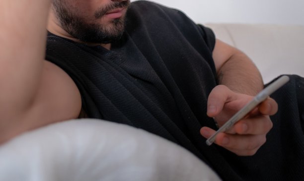 无聊的年轻男人坐在沙发上浏览网络图片下载