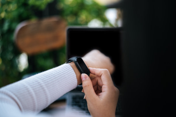 年轻女子在咖啡馆使用智能手表和笔记本电脑图片下载