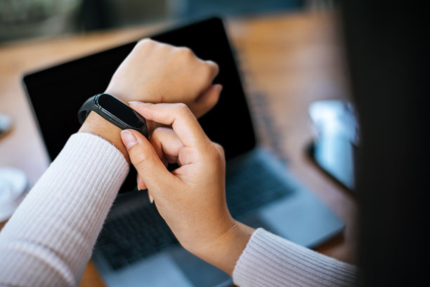 年轻女子在咖啡馆使用智能手表和笔记本电脑图片下载