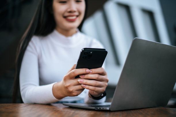 年轻女子在咖啡馆使用智能手机和笔记本电脑图片下载