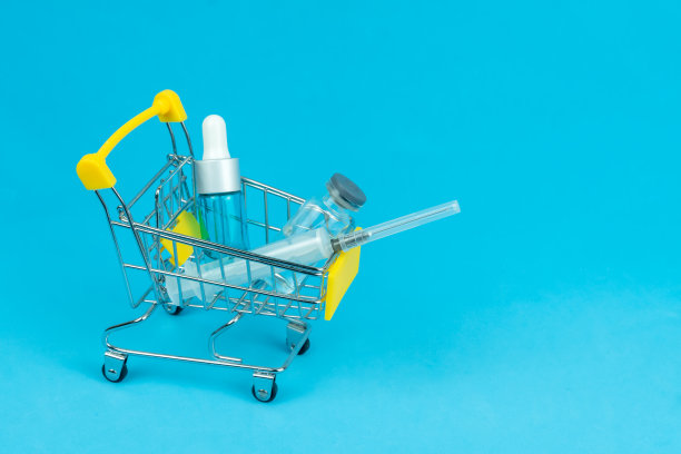 购物车里有蓝色背景的医疗安瓿和注射器，复制空间。购药观念，提高药价图片下载
