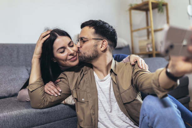 美丽的年轻情侣在一起坐在沙发上自拍图片下载