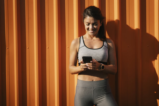 年轻健康的女人在训练后休息时使用电话。图片下载