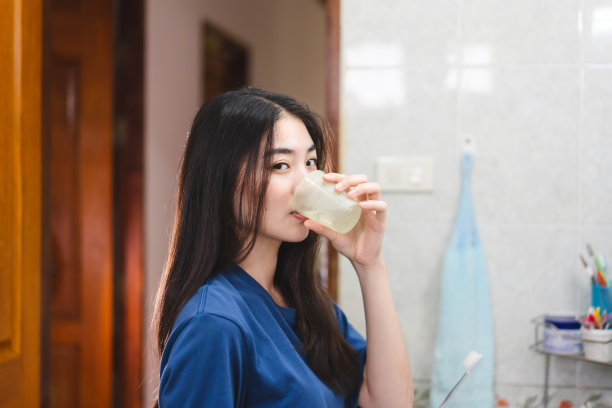 年轻的成年亚洲妇女在浴室喝水和刷牙牙科保健图片下载