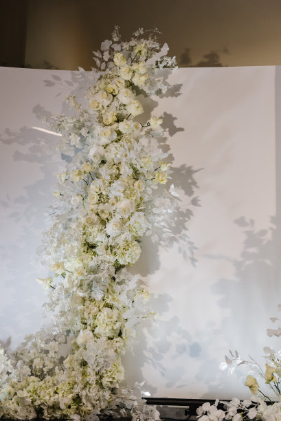 豪华婚宴在大厅餐厅举行。副本的空间。照片墙上，拱门处装饰着花瓣、鲜花。庆典洗礼概念。宴会区生日派对的时尚装饰。图片下载