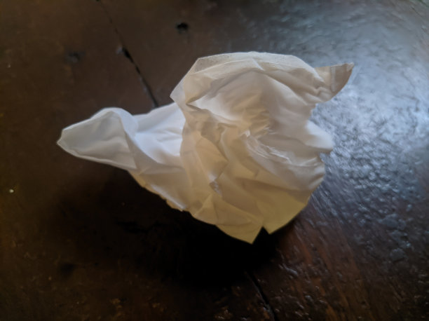 用过的纸巾放在棕色的桌子上。组织在中间图片下载