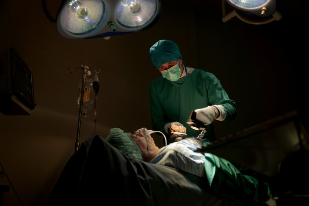 手术室里穿着绿色制服的队医正在抢救正在做心脏手术的危重病人他们有标准化的手术工具救生工具比如心脏泵图片下载