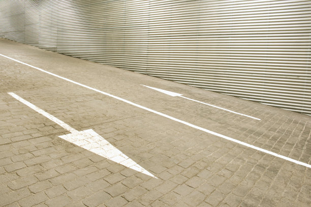 通往地下车库的入口坡道，地面上绘有移动方向的白色箭头图片下载