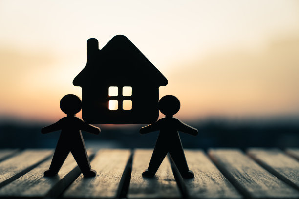 两个人互相扶着房子的模型。家庭的概念。分期付款和购房家庭维护。图片下载