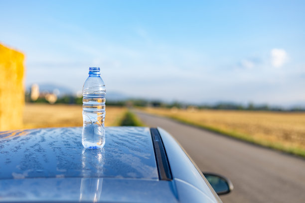 西班牙巴斯克地区。夏日早晨，停在乡间小路旁的汽车车顶上的一瓶水图片下载