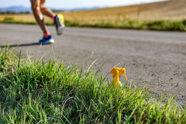 乡间小路上的草地旁有一瓶防晒霜。在柏油路上跑的走焦者图片下载