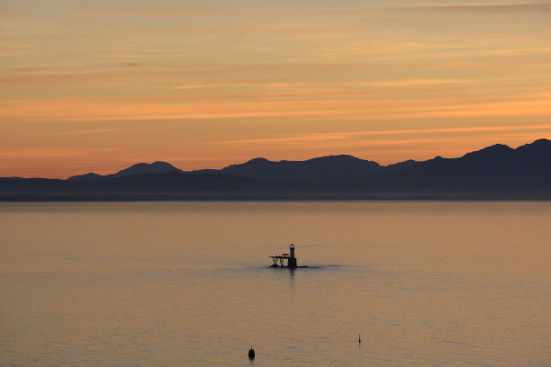 日出在大西洋南非佛斯湾的罗马岩石灯塔上图片下载
