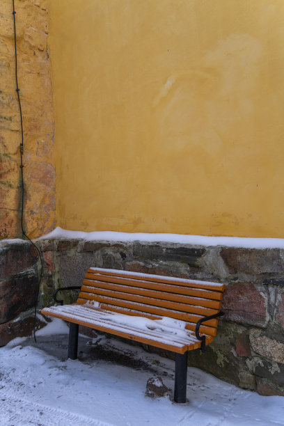 黄石墙旁的木凳上覆盖着雪图片下载