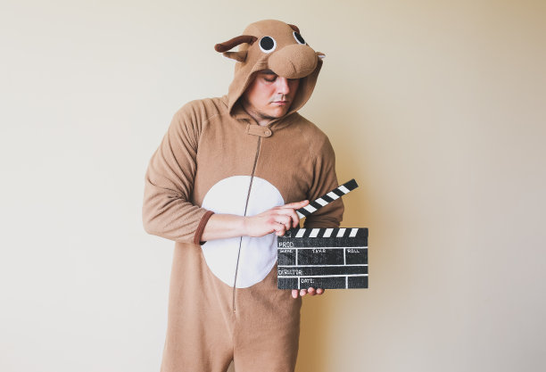 男子在cosplay服装拿着黑色隔板。穿着搞笑动物睡衣的家伙在拍电影。导演和业余电影。创造性的概念。日本动漫。图片下载