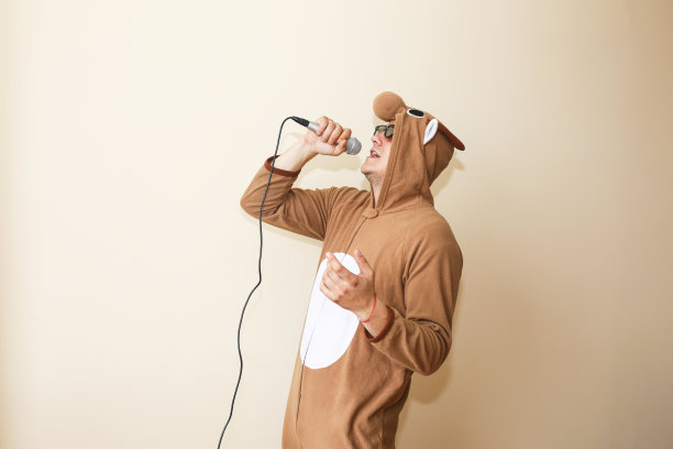 男人在角色扮演服装牛唱卡拉ok。穿着搞笑动物睡衣的家伙拿着麦克风。有趣的照片。图片下载