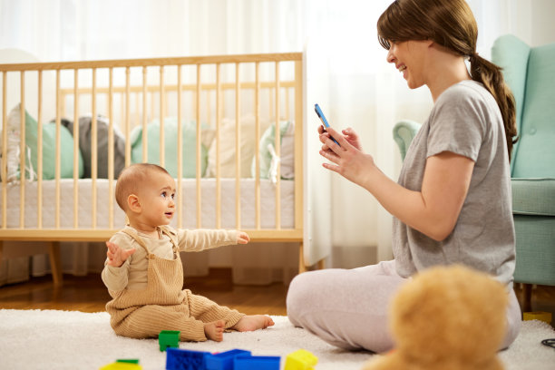 快乐的母亲在家里给她的男婴拍照图片下载