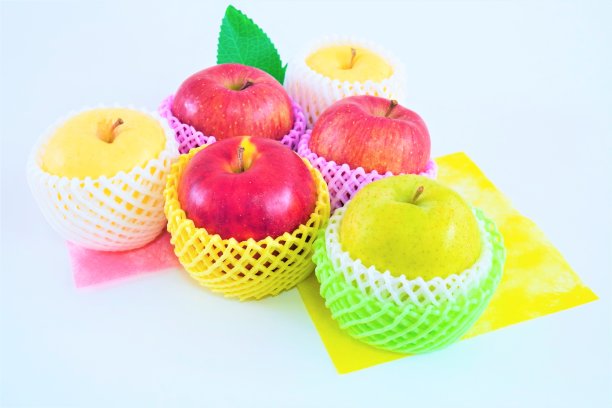 六个带着各种网盖的苹果，摆放在彩色的粉色和黄色的日本纸上，底色为白色图片下载