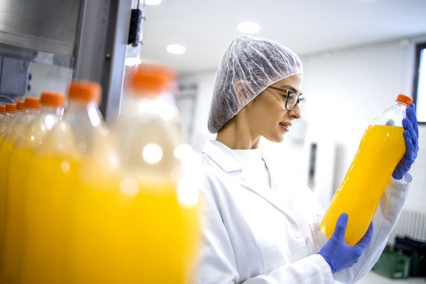 女食品技师在装瓶厂做橙汁质量控制。图片下载