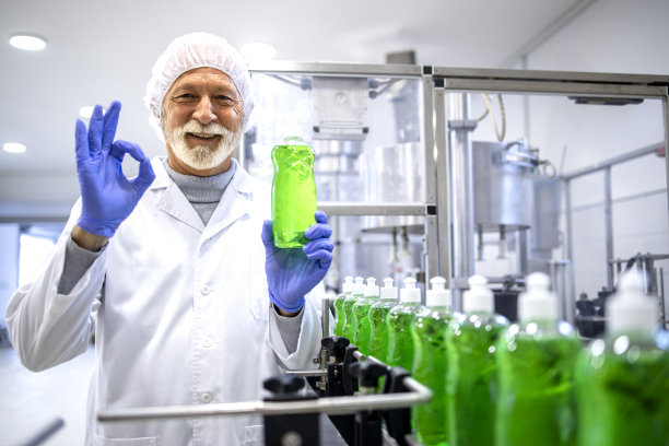 成功生产清洁用品。身穿白色无菌制服的工厂工人在化工厂拿着洗涤剂的照片。图片下载