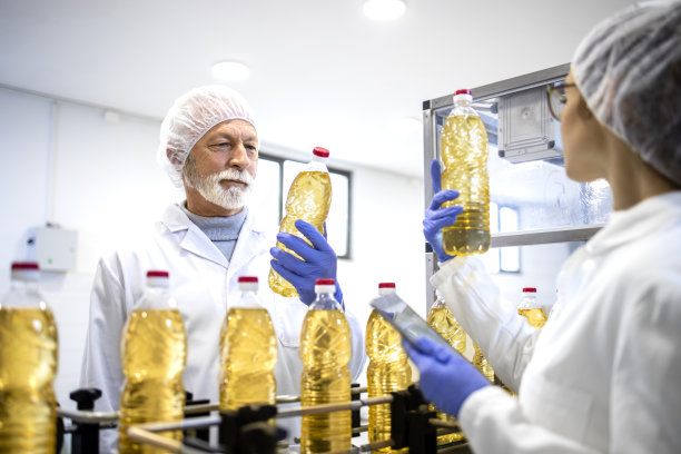 食品厂工人站在生产机器旁，控制产品质量。图片下载