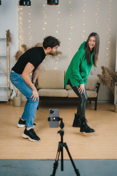 一对有趣的网红在手机上为社交网络拍摄舞蹈视频，在家里玩得很开心。广播网络图片下载