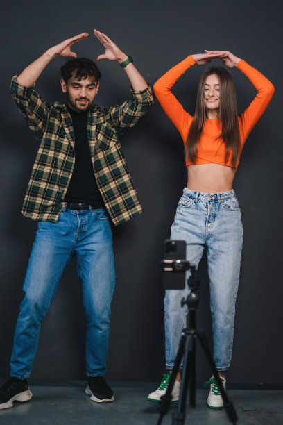 白人夫妇在智能手机上进行舞蹈视频挑战，在黑色背景上隔离。视频博客。z世代社交网络内容图片下载