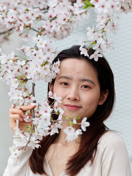 美丽的年轻中国女孩的户外肖像与盛开的白色樱花背景在春天的花园，美丽，夏天，情感，生活方式，表达和人的概念。图片下载