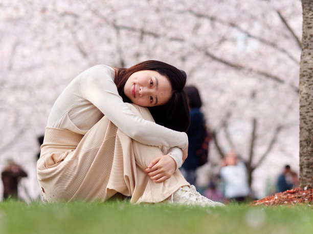 美丽的年轻中国女孩坐在草地上的户外肖像，在春天的花园，美丽，夏天，情感，生活方式，表达和人的概念。图片下载