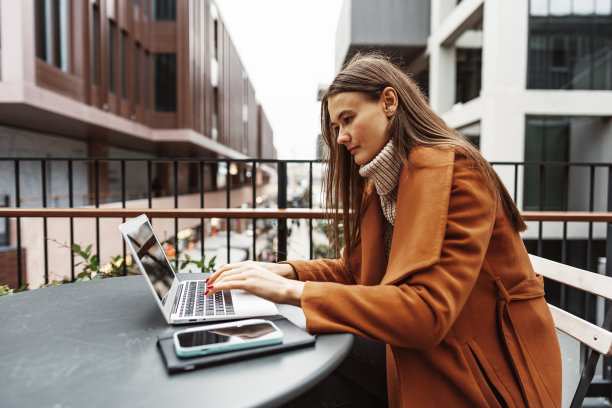 年轻女子工作与她的笔记本电脑坐在桌子在街上图片下载
