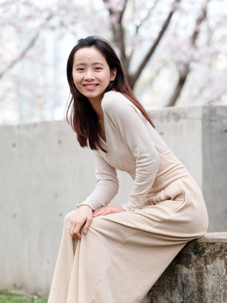 户外肖像美丽的年轻中国女孩坐在盛开的白色樱花背景在春天的花园，美丽，夏天，情感，生活方式，表达和人的概念。图片下载