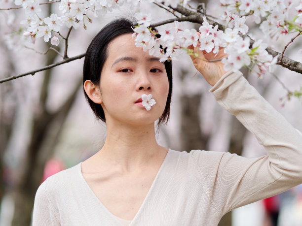 美丽的年轻中国女孩的户外肖像与盛开的白色樱花背景在春天的花园，美丽，夏天，情感，生活方式，表达和人的概念。图片下载
