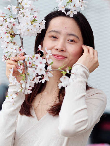 美丽的年轻中国女孩的户外肖像与盛开的白色樱花背景在春天的花园，美丽，夏天，情感，生活方式，表达和人的概念。图片下载