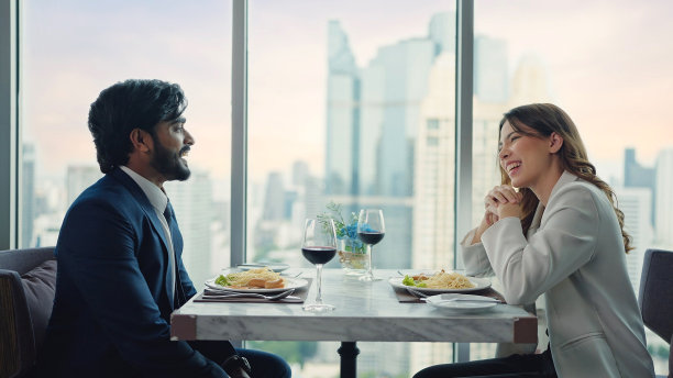 快乐的商业夫妇聊天，享受在餐厅和城市景观中吃食物和喝葡萄酒图片下载