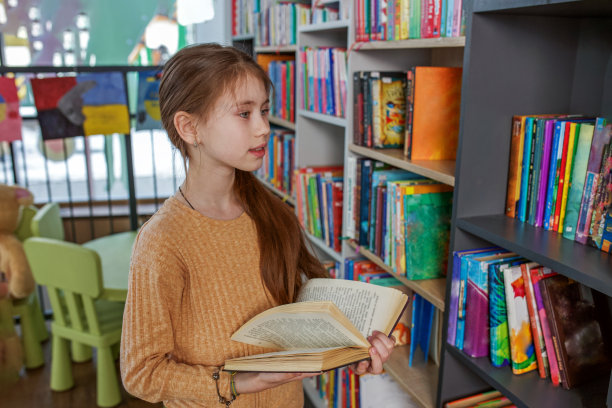 小女孩在学校图书馆选书。学校教育。每天阅读的好处。图片下载