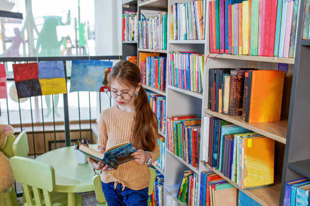 小女孩在学校图书馆选书。学校教育。每天阅读的好处。图片下载