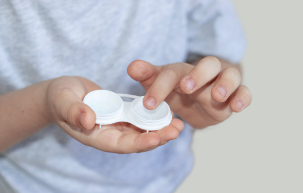 孩子把隐形眼镜放在手指上，从箱子里拿出来图片下载