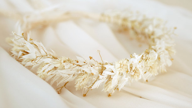 白色的干花花环躺在婚纱上。(特写)。图片下载