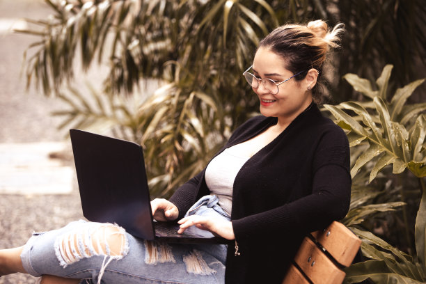 年轻女子在花园里用笔记本电脑在家工作图片下载