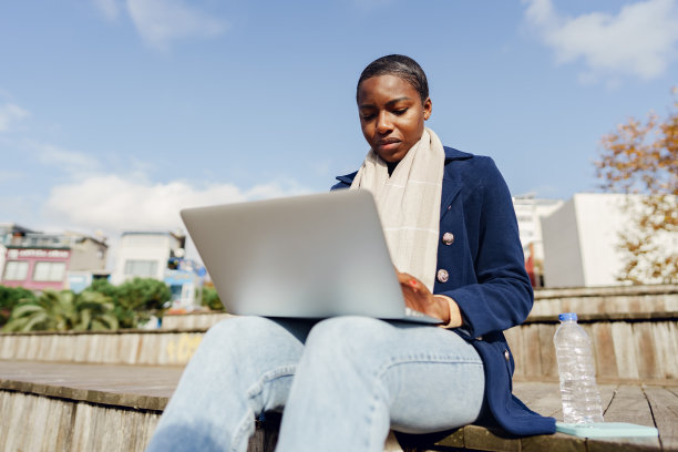 年轻的非洲女商人坐在城市的长椅上使用笔记本电脑图片下载