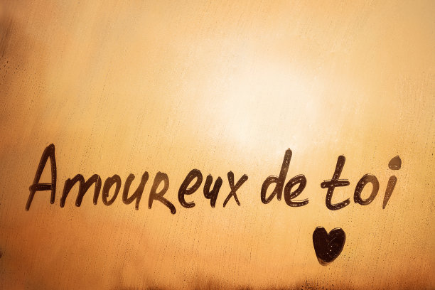橙色晚霞窗上，用心形字体用法文“Amoureux de toi”表示“爱上你了”图片下载
