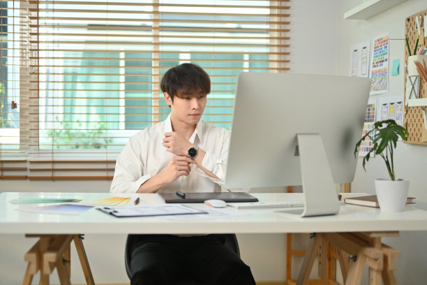 英俊的亚洲男性网站开发人员在他的工作站工作的移动应用软件设计项目。图片下载