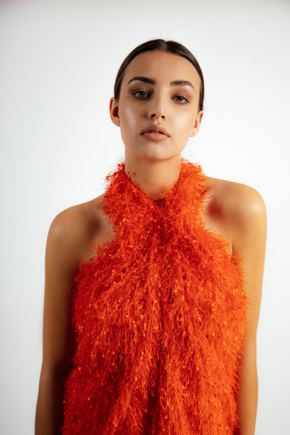 年轻迷人的女人长黑发的肖像，化妆穿着蓬松的橙色吊带连衣裙在白色的背景。图片下载