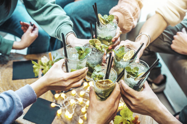 快乐的朋友群欢呼莫吉托饮料在高档酒吧餐厅-年轻人有乐趣敬酒鸡尾酒杯享受欢乐时光在屋顶酒吧-派对时间，生活方式和青年概念图片下载